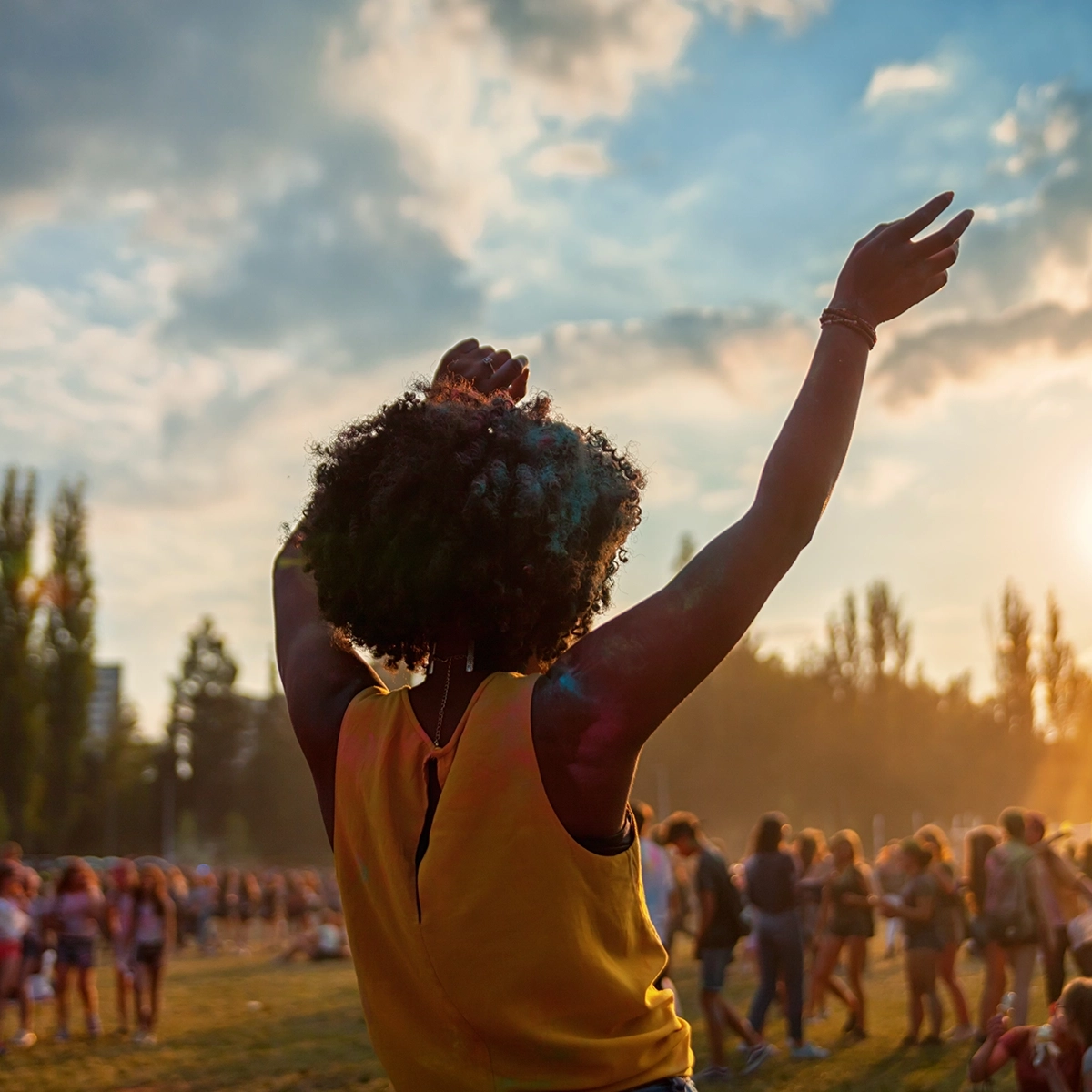 Woman wearing a pink Nike sweatshirt, large novelty pineapple sunglasses, a colorful flower lei, and a green grass skirt with flower decorations, dressed in a tropical-themed outfit at One More Lap for Kids' Village 2024.